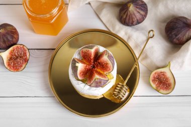 Peynirli pano, taze incir ve hafif ahşap arka planda bir kavanoz bal.