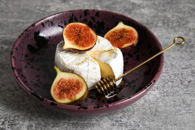 Peynirli tabak, taze incir ve gri arka planda bal.