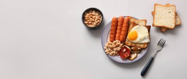 Gri arka planda sahanda yumurtalı lezzetli İngiliz kahvaltısı.