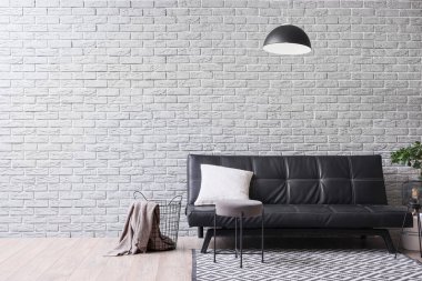 Oturma odasında siyah kanepe, sepet ve lamba var.