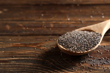 Ahşap arka planda chia tohumları olan kaşık, yakın plan