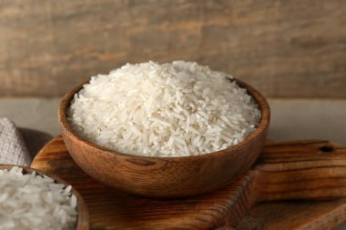 Gri masadaki çiğ pirinçli ahşap kase.