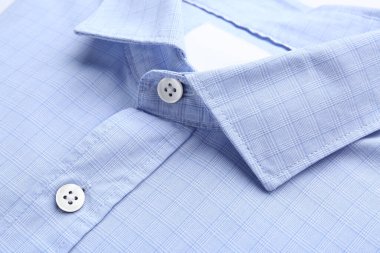 Beyaz arka planda katlanmış mavi yakalı gömlek, yakın plan.