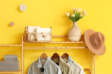 Asılı elbiseli palto askısı, lale çiçekleri ve şık bir koridorda şapka, yakın plan.