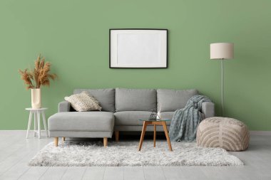 Gri kanepesi, cam masası ve boş çerçevesi olan şık bir oda.