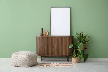 Ahşap dolap, dekoratif ve yeşil duvarın yanında boş çerçeve.