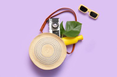 Leylak arka planında fotoğraf makinesi ve plaj aksesuarları olan kompozisyon