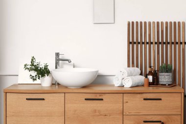 Lavabosu ve banyo aksesuarları olan şık ahşap bir şifonyer.