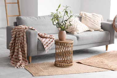 Kahve masasında gri kanepe ve bambu sapları olan şık bir oturma odası.