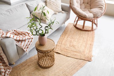 Kahve masasında gri kanepe, koltuk ve bambu sapları olan şık bir oturma odası.