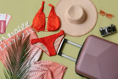 Çantalı kompozisyon, mayo, fotoğraf makinesi ve yeşil arka planda plaj aksesuarları, yakın plan.