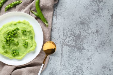 Gri zemin üzerinde püre yeşil bezelye ile tabak