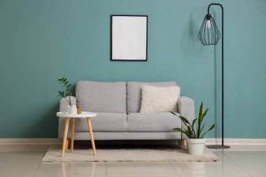 Gri kanepesi, çiçekleri ve standart lambası olan şık bir oturma odası.