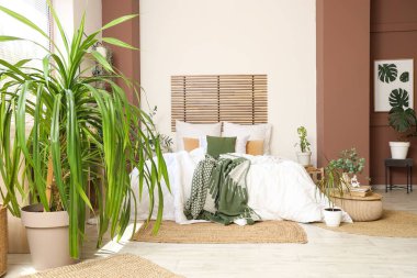 Konforlu yatağı ve çiçekleri olan modern bir yatak odası.