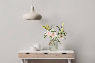 Güzel çiçekli vazo ve gri duvarın yanındaki masada bir fincan çay.