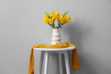 Gri duvarın yanındaki masada güzel çiçekli vazo.