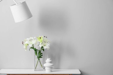 Gri duvarın yanındaki masada güzel çiçekli vazo.