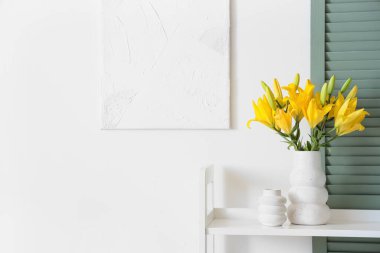 Beyaz duvarın yanındaki raflarda güzel zambak çiçekleri olan vazo.