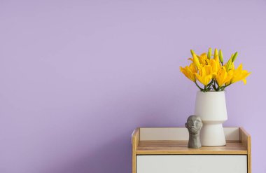 Leylak duvarının yanındaki masada güzel çiçekli vazo.