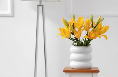 Beyaz duvarın yanındaki masada güzel çiçekli vazo.