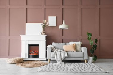 Gri kanepe, hasır puf ve şık şömineli rahat bir oturma odası.