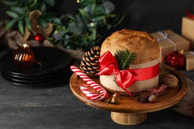 Tatlı Noel Panettone 'u ve şeker bastonuyla siyah ahşap masada dur.