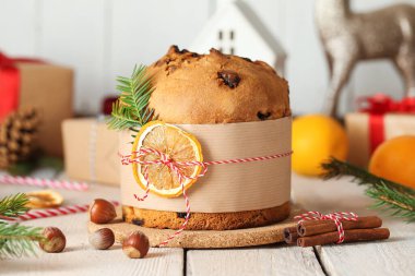 Köknar dallı tatlı Noel Panettone, kurutulmuş portakal dilimi ve beyaz ahşap arka planda tarçın