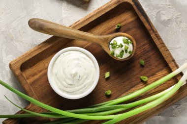Kase ve bir kaşık lezzetli ekşi krema ve grunge masasında doğranmış yeşil soğan.