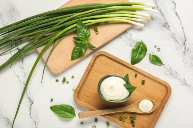 Lezzetli ekşi krema ve beyaz mermer masada taze yeşillik ile kesme tahtaları.