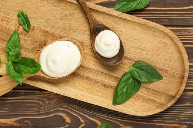 Lezzetli ekşi krema ve ahşap masada taze fesleğenle kesme tahtası.