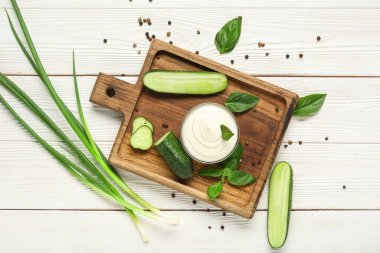 Lezzetli ekşi krema ve beyaz ahşap masada taze yeşillik ile kesme tahtası.