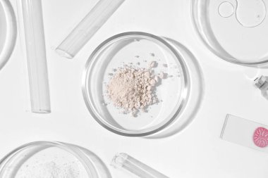Beyaz arka planda toz ve laboratuvar ekipmanları bulunan petri kapları