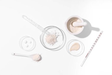 Beyaz zemin üzerinde toz ve laboratuvar ekipmanı bulunan petri kabı