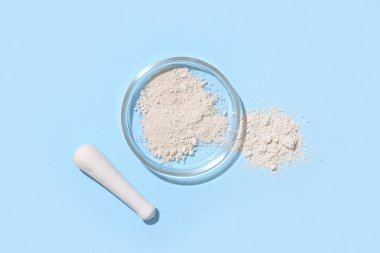 Mavi zemin üzerinde pudra ve tokmak olan petri kabı