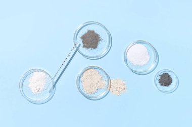 Farklı tozlara sahip bir petri kabı ve mavi arka planda mezun olmuş bir damlatıcı.