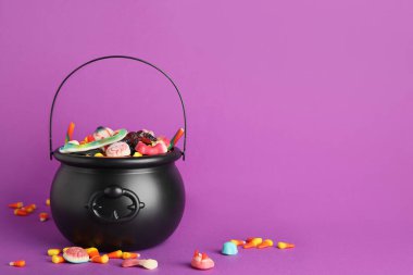 Mor arka planda farklı tatlı Cadılar Bayramı jöleli şekerlerinden oluşan bir kazan.