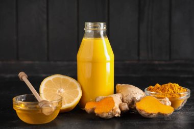 Bir şişe sağlıklı zerdeçal içeceği ve siyah grunge arkaplan malzemesi.