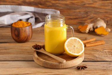 Tepsi, bir kavanoz sağlıklı zerdeçal ve ahşap arka planda malzemeler, yakın plan.