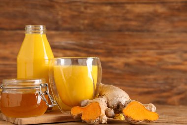 Cam, bir şişe sağlıklı zerdeçal ve ahşap arka planda malzemeler, yakın plan.