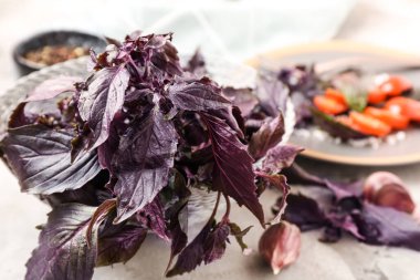 Gri arka planda taze mor fesleğen yapraklı sepet, yakın plan.