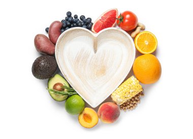 Kalp şeklinde tabaklar, farklı taze sebzeler ve beyaz arka planda izole meyveler. Dünya Vejetaryen Günü