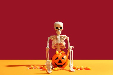 Mısır şekerli balkabağı ve mor arka planda turuncu masada iskelet. Cadılar Bayramı