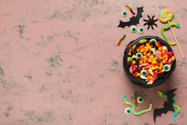 Cadılar Bayramı için bir kap lezzetli şekerle kompozisyon ve grunge arka planda kağıt yarasalar