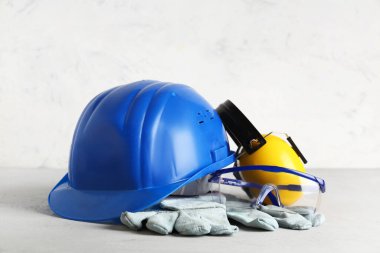 Sert şapka, koruyucu kulaklıklar ve beyaz grunge arka planda güvenlik gözlükleri.