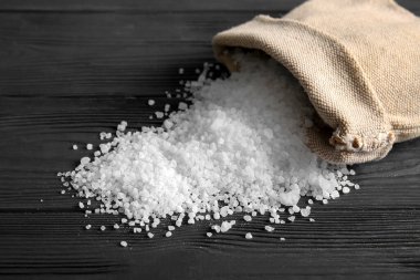 Koyu ahşap arka planda deniz tuzu dolu çuval.