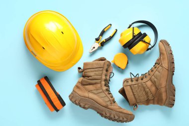 Mavi arka planda sert şapka, botlar ve güvenlik ekipmanları