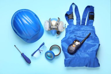 Mavi arka planda sert şapka, üniforma ve güvenlik ekipmanları