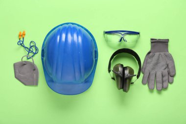 Yeşil arka planda sert şapka ve güvenlik ekipmanları