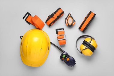 Koruyucu kulaklıkları, emniyet kemerleri ve gri arka planda radyo vericisi olan bir şapka.