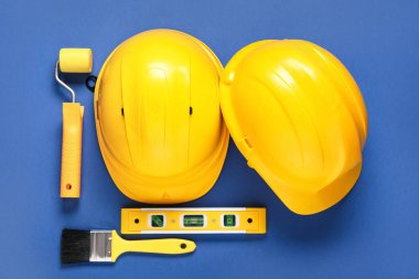 Mavi arka plan, üst görünüm üzerine sert başlıklar ve inşaat araçları